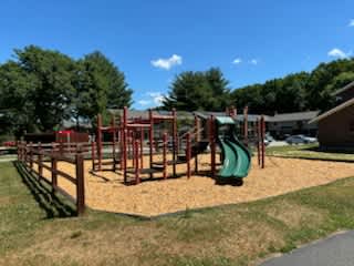 A playground with a green slide and a red structure.