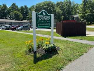 A sign for Presidential Gardens Apartments stands in a grassy area.