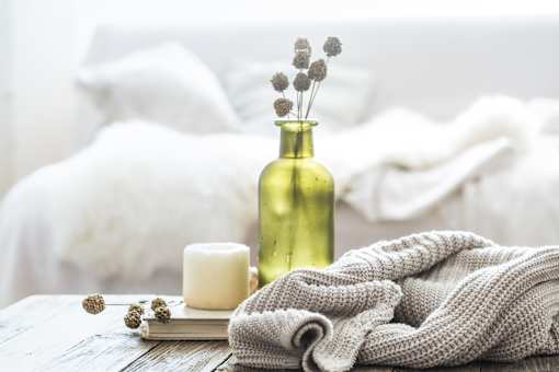 a bed with a blanket and a vase of flowers on a table