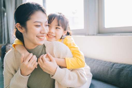 A woman is holding a child close to her chest.