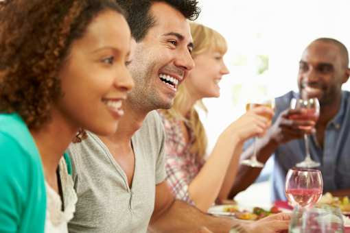 a group of people sitting around a table eating and drinking wine