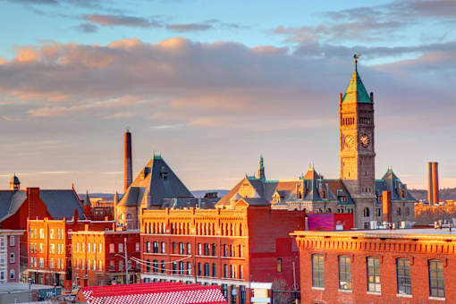 A cityscape with a prominent clock tower stands tall against a twilight sky.