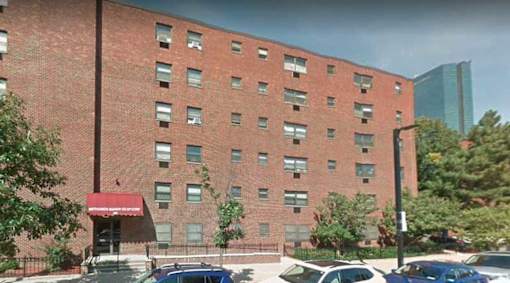 A red brick building with a red awning and cars parked in front.