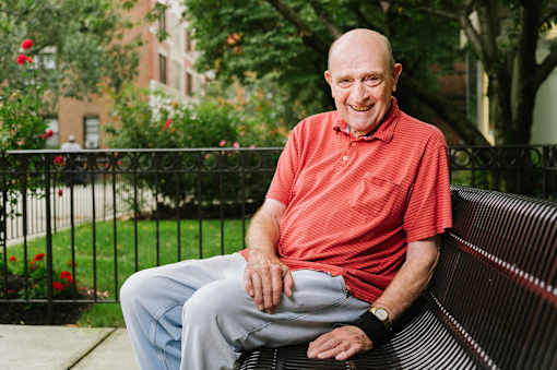 A man in a red shirt is sitting on a bench.