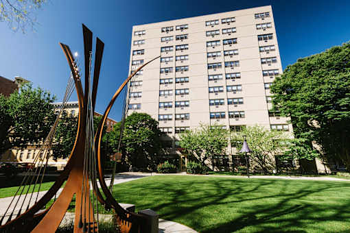 A large sculpture sits in front of a building with many windows.