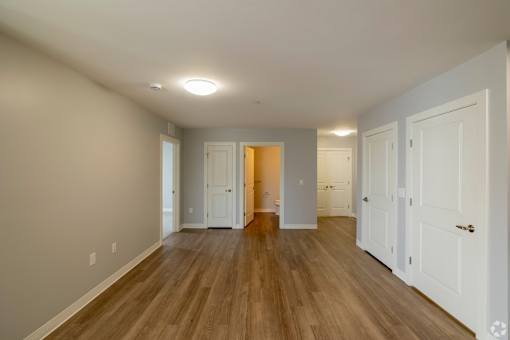 A room with white walls and wooden floors, with a door in the middle of the room.