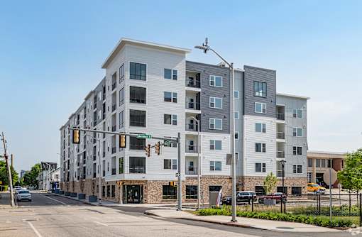 A modern apartment building with a parking lot in front.