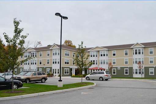 Apartment complex with a parking lot in front.
