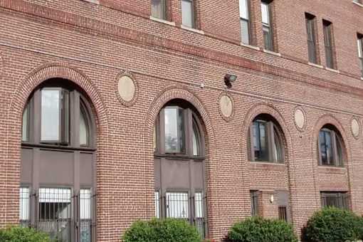 A red brick building with arched windows and a security camera on the top.