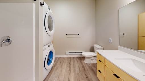A modern bathroom with a washer and dryer built into the wall.