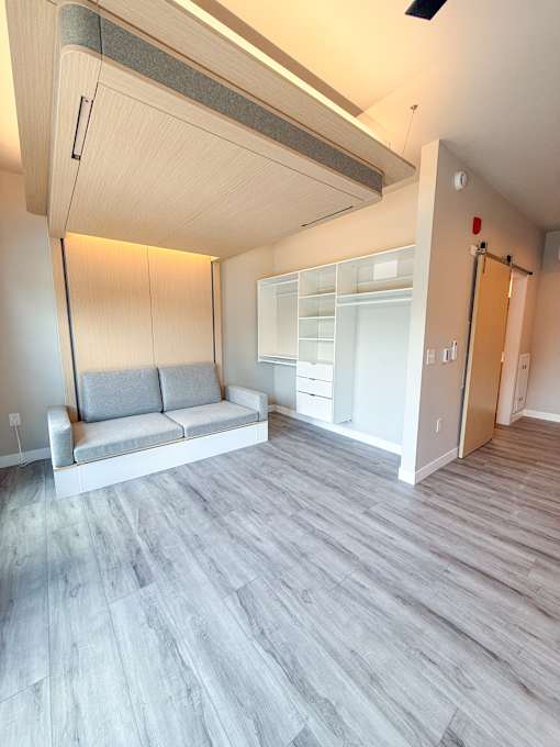 A room with a grey sofa and wooden flooring.