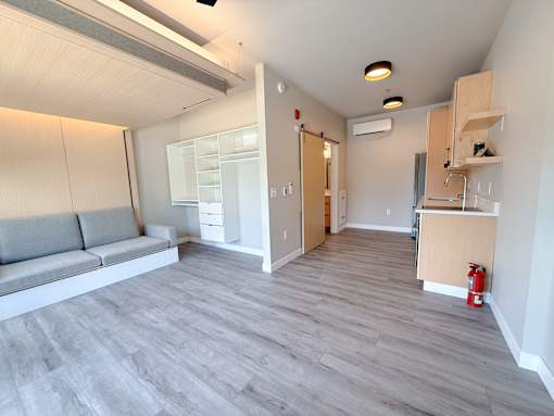 A living room with a grey sofa and a grey floor.