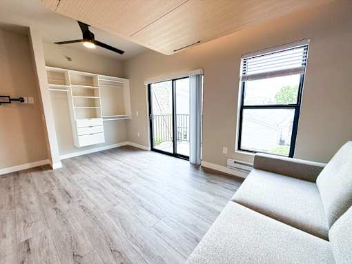 A living room with a couch, sliding glass doors, and a ceiling fan.