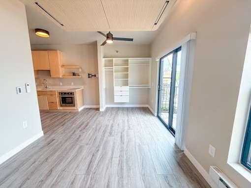 A spacious kitchen with wooden flooring and a ceiling fan.