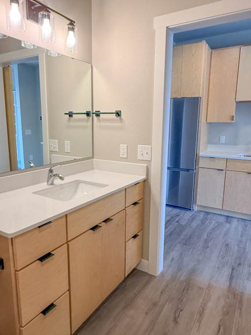 A bathroom with a sink, mirror, and wooden cabinets.