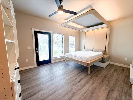 A bedroom with a bed, a window, and a ceiling fan.