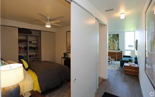 A bedroom with a bed, a nightstand, and a lamp.