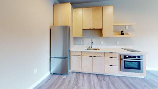 A kitchen with wooden cabinets and a stainless steel refrigerator.
