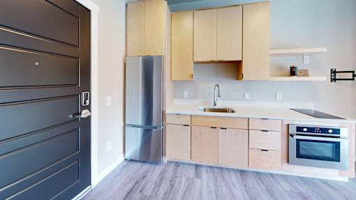A modern kitchen with wooden cabinets and a stainless steel refrigerator.