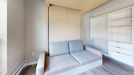 A grey couch with a white drawer unit to the right.