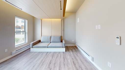 A living room with a grey couch and wooden floors.