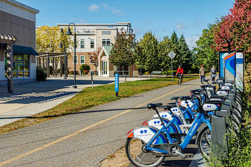 A row of blue bikes are parked on the side of a street.