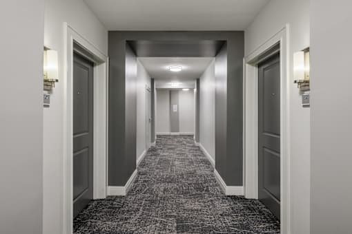 A long hallway with doors on both sides and lights on the ceiling.