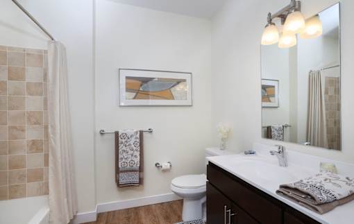 A bathroom with a toilet, sink, and a painting on the wall.