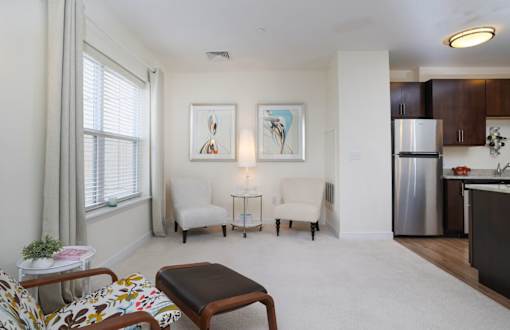 A living room with a couch, chair, ottoman, and a painting on the wall.