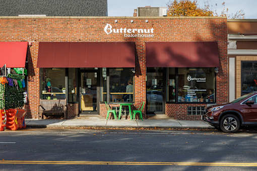 A Butternut bakehouse with a red awning and a red car parked in front.