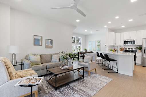a living room with a couch and a coffee table and a kitchen with a counter