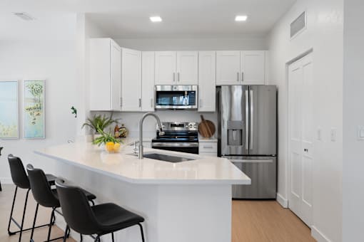 a kitchen with a large island and a stainless steel refrigerator