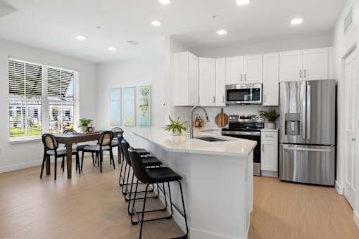 a large white kitchen with a large island and stainless steel appliances