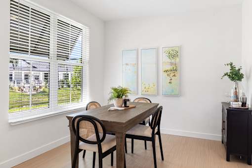 a dining room with a wooden table and chairs and a large window