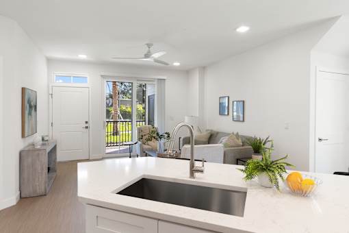 an open kitchen and living room with white walls and white counter tops and a sink