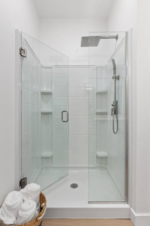a shower with a glass door in a white bathroom