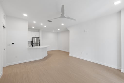an empty living room with white walls and a ceiling fan
