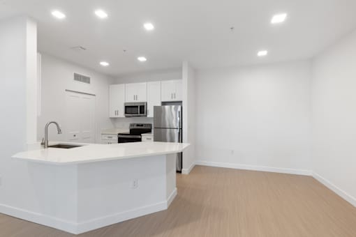 a white kitchen with a large island and a stainless steel refrigerator