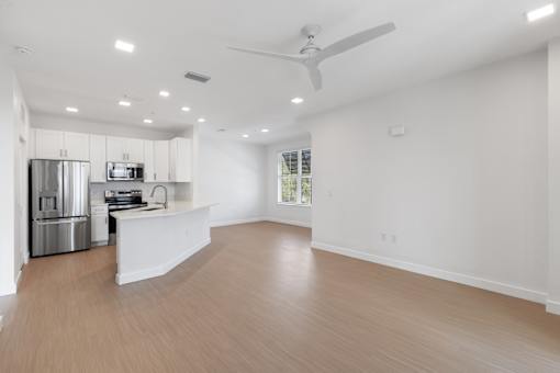 an empty living room and kitchen with a ceiling fan