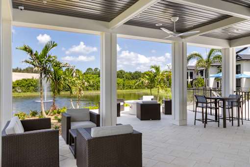 a covered patio with a view of a body of water and palm trees