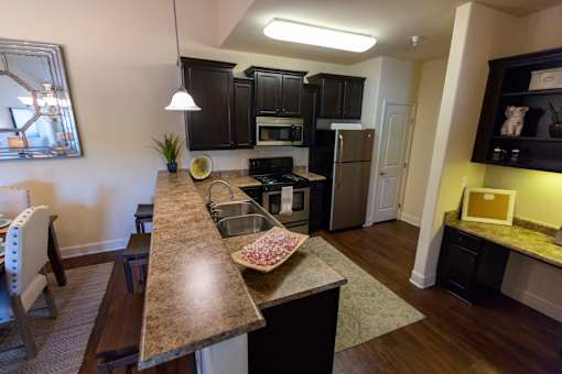 A kitchen with a granite countertop and black cabinets. at The Villas at Nature Walk, Huntsville, Alabama