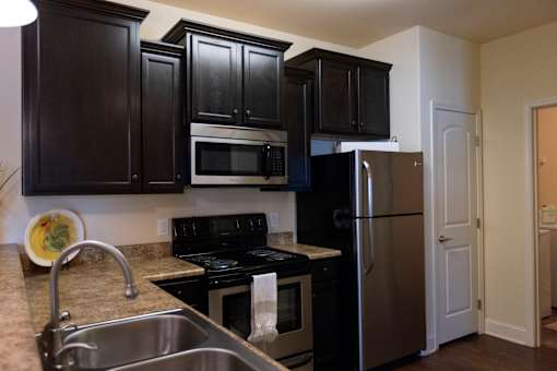 A kitchen with black cabinets and stainless steel appliances. at The Villas at Nature Walk, Huntsville, AL, 35824