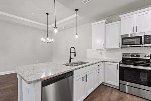 A modern kitchen with white cabinets and stainless steel appliances. at The Villas at Nature Walk, Huntsville, AL, 35824