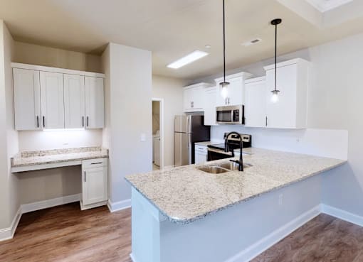 A kitchen with a granite countertop and a microwave above it. at The Villas at Nature Walk, Huntsville, 35824