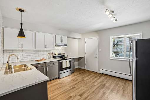 A kitchen with a black fridge and wooden floors.