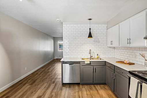 A kitchen with a white tile backsplash and wooden floors.