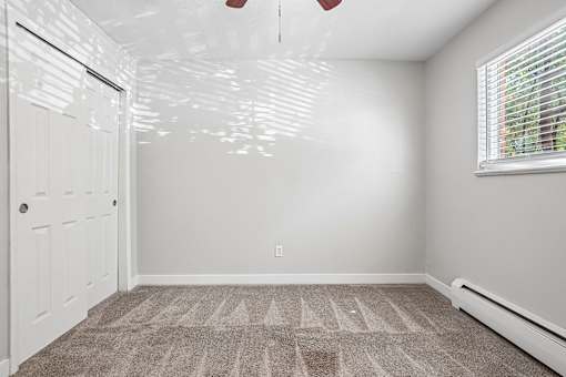 A room with a carpeted floor and a window with blinds.