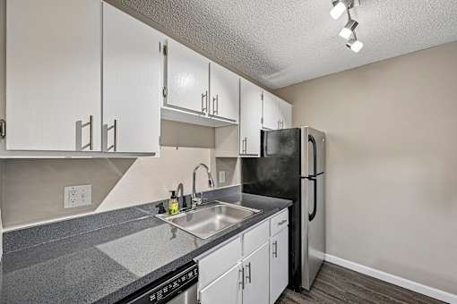 A kitchen with a black refrigerator and white cabinets.