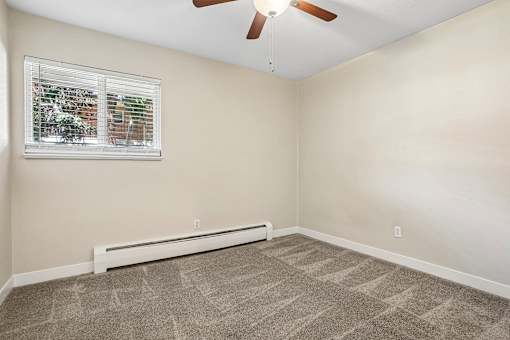 A room with a ceiling fan and a window with blinds.