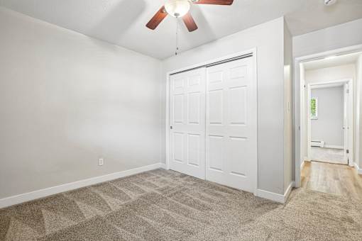 A room with a white door and a ceiling fan.